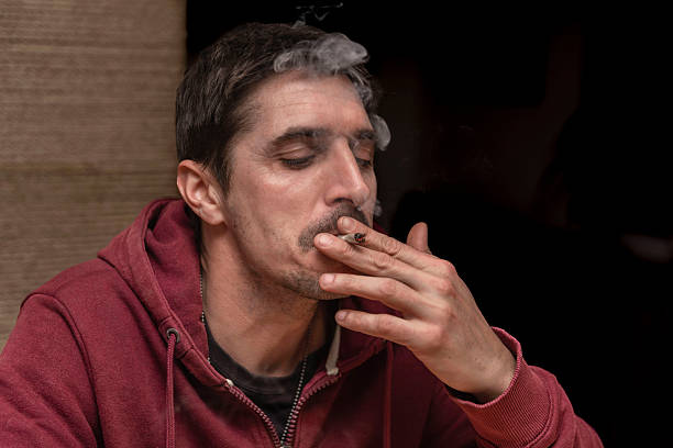 A person smiling and relaxed, enjoying the effects of the Melon Berry strain, with vibrant green and purple nugs visible in the foreground.